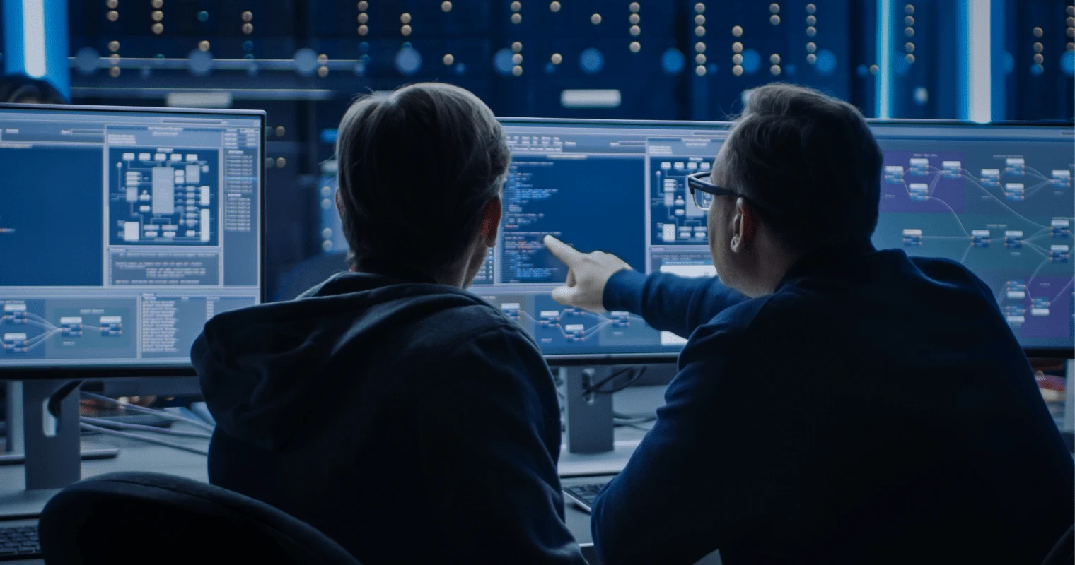 Mitarbeiter bei detacon zeigt einem Kollegen etwas auf seinem Monitor