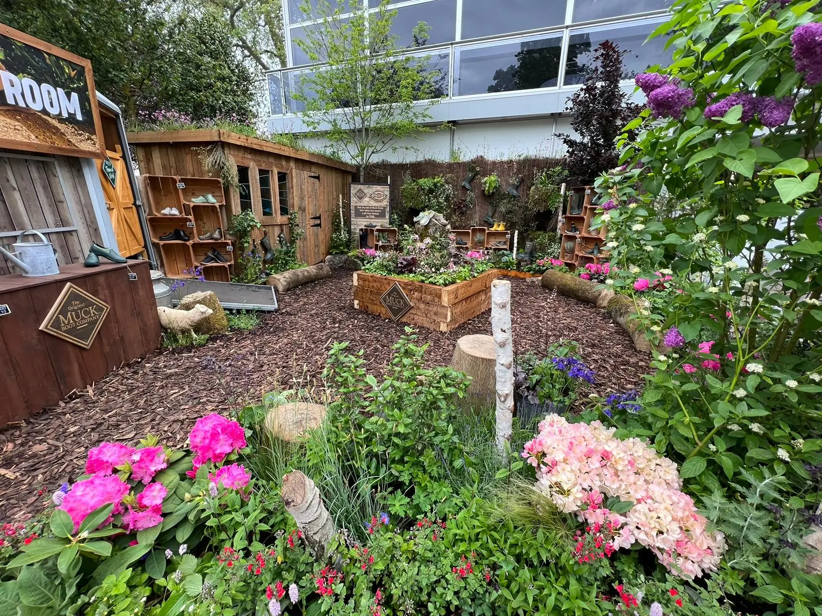 A vibrant garden with colorful flowers, wooden structures, and a sunny backdrop, creating a serene outdoor space.