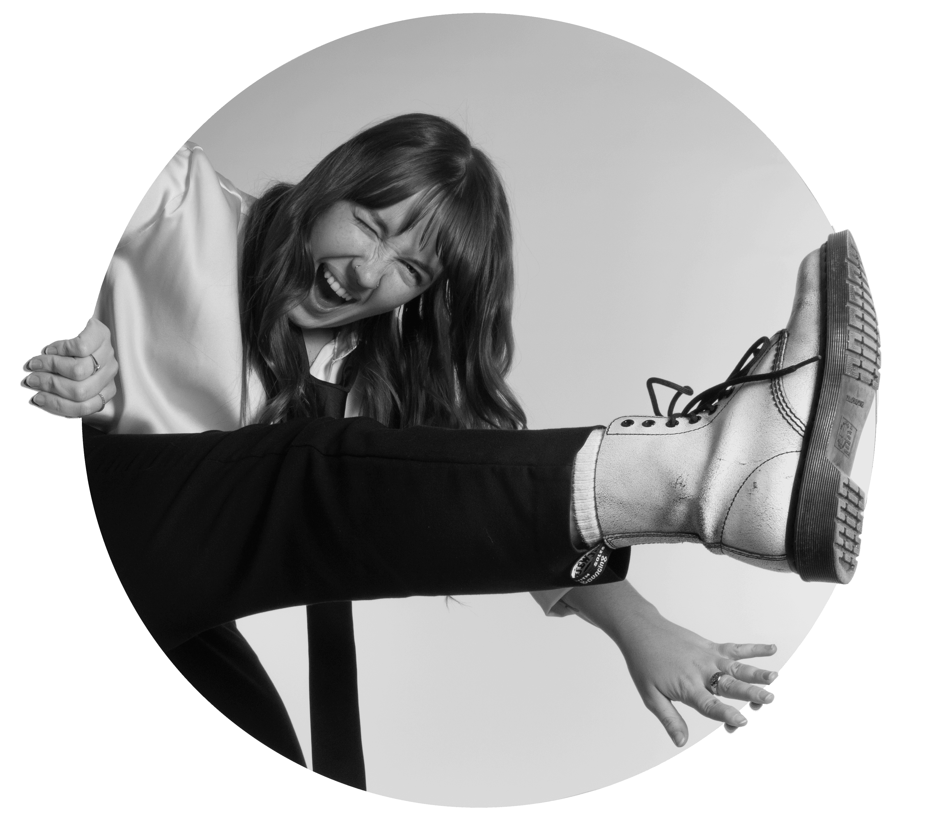 A black and white image featuring a person reclining with their legs extended, wearing stylish footwear.