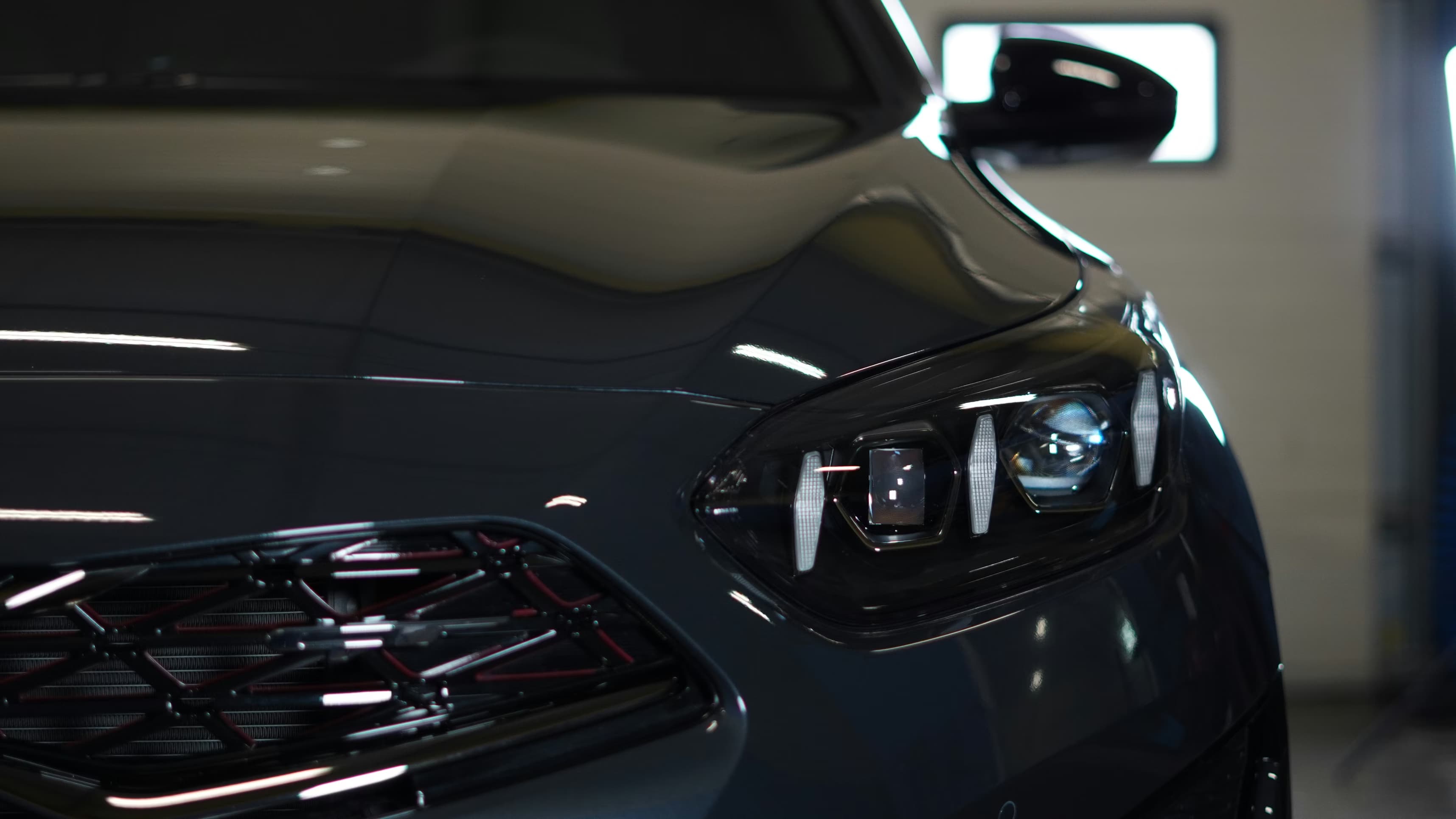 Détail de la face avant d’une voiture grise avec phare LED et calandre noire brillante