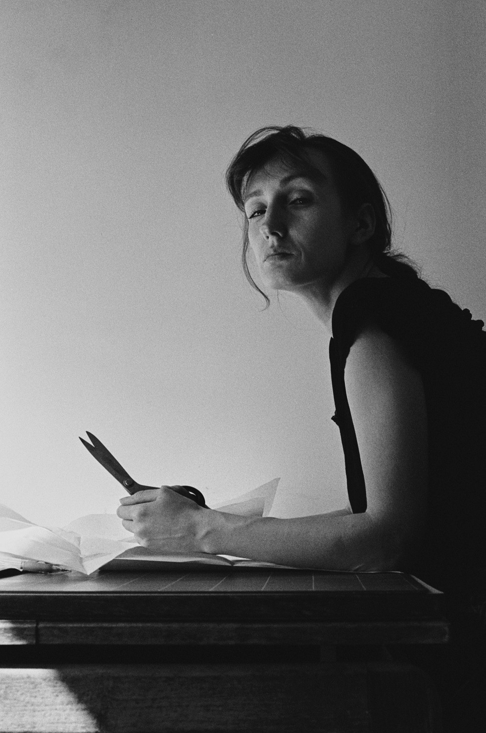 Black and white image of a woman holding scissors and looking at the camera