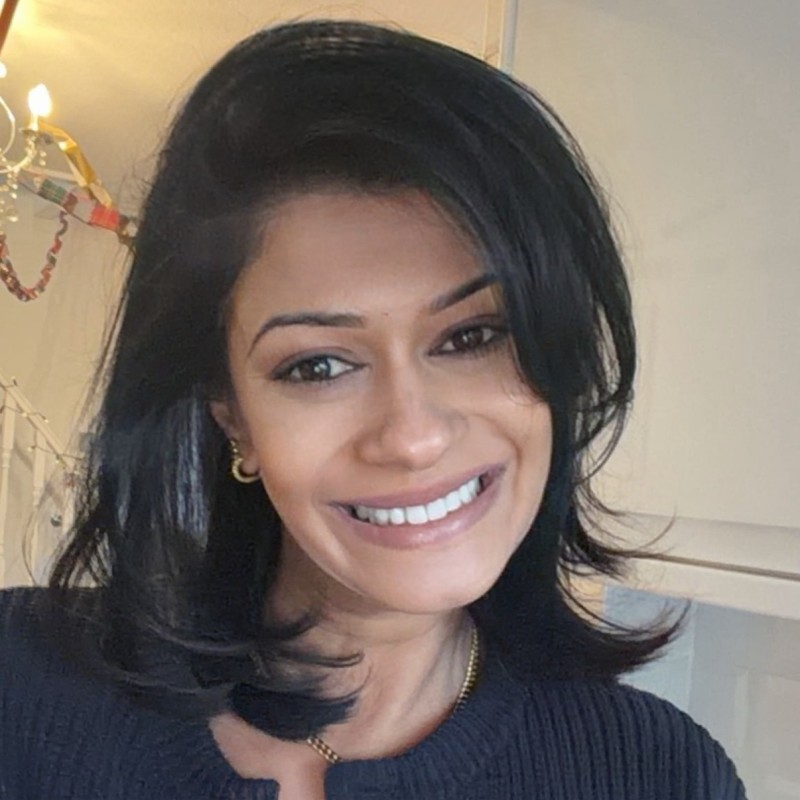 A Young woman in grey blueish background smiling