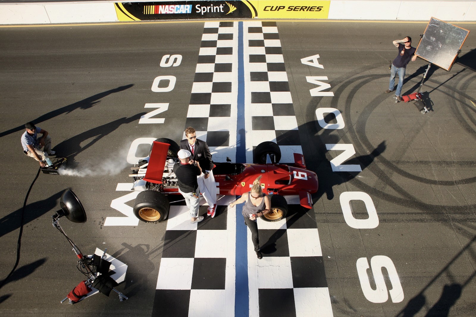 Production crew surrounding a race car on a track