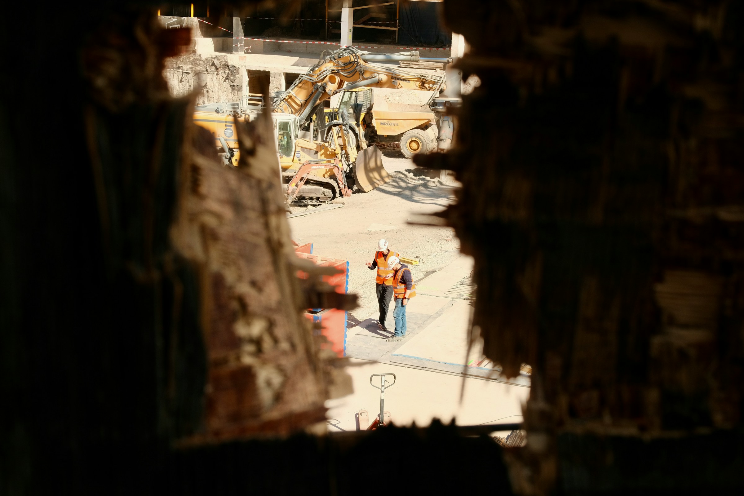 Construction workers observe a demolition site with heavy machinery