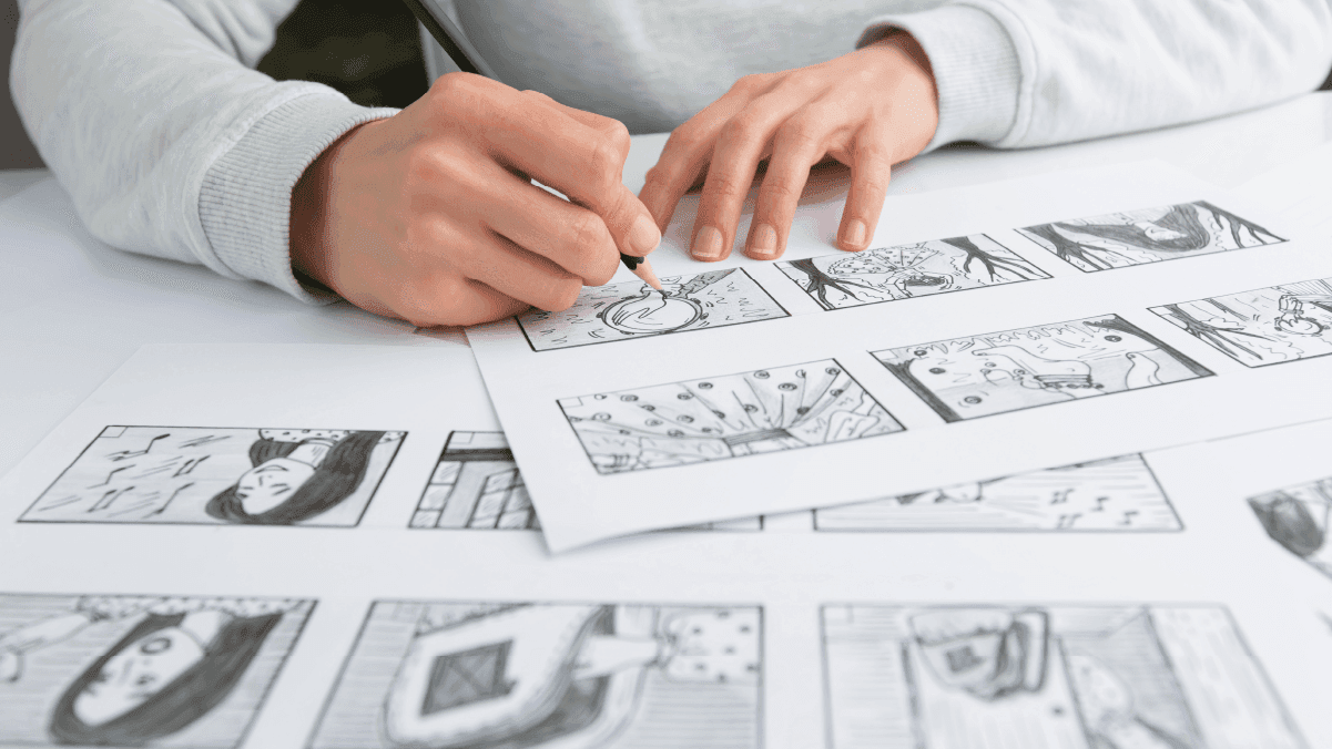 Designer drawing storyboard frames with detailed black-and-white sketches laid out on a table
