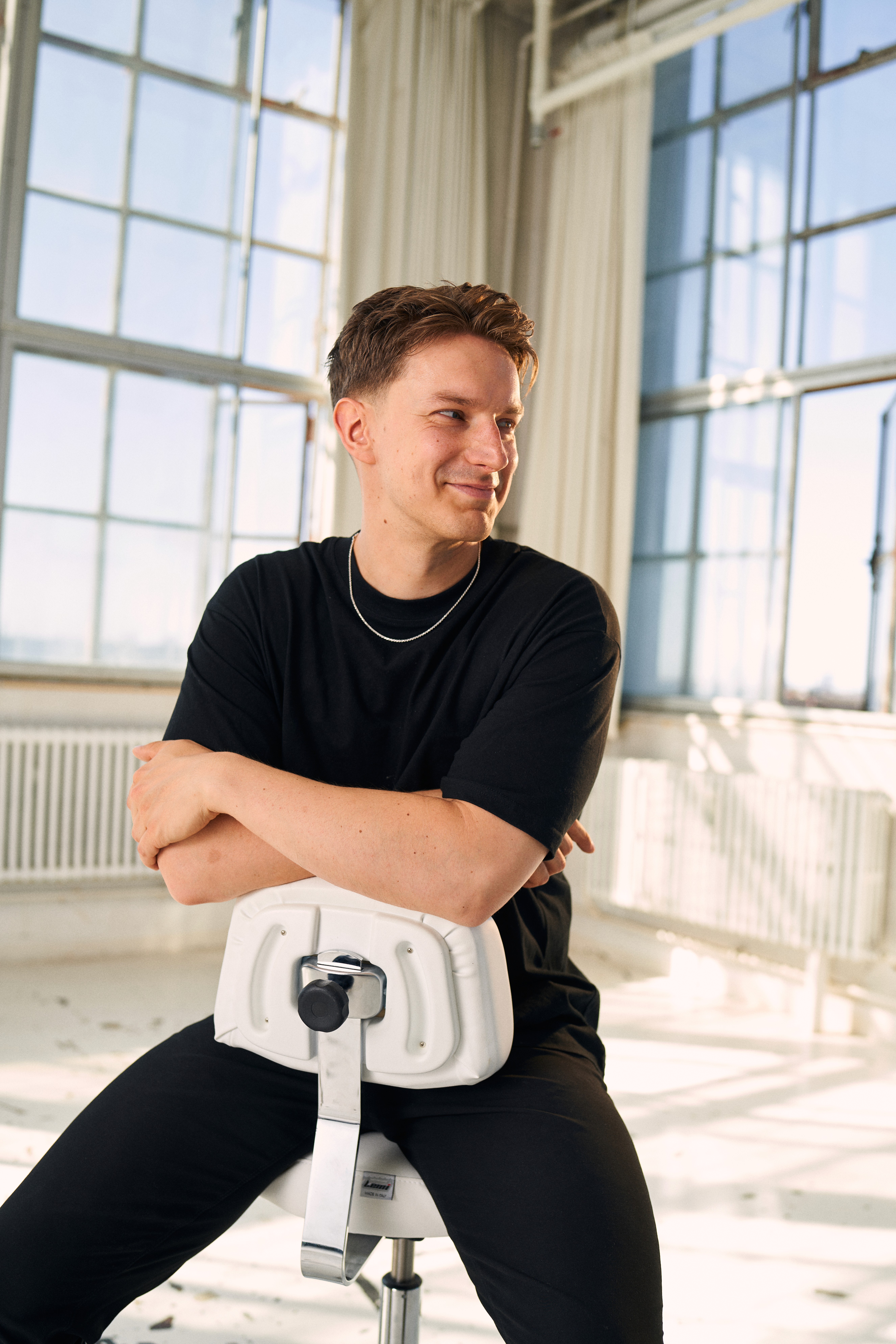 A thoughtful young person with dark hair gazes to the side, captured in soft black and white lighting.
