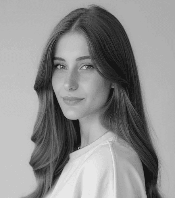 A thoughtful young person with dark hair gazes to the side, captured in soft black and white lighting.
