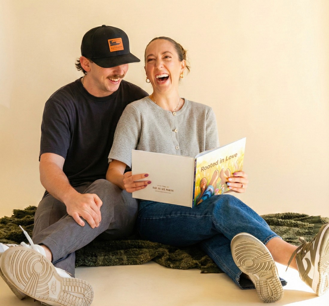 A smiling young man with crossed arms, wearing a plaid shirt and white t-shirt, poses against a dark background.