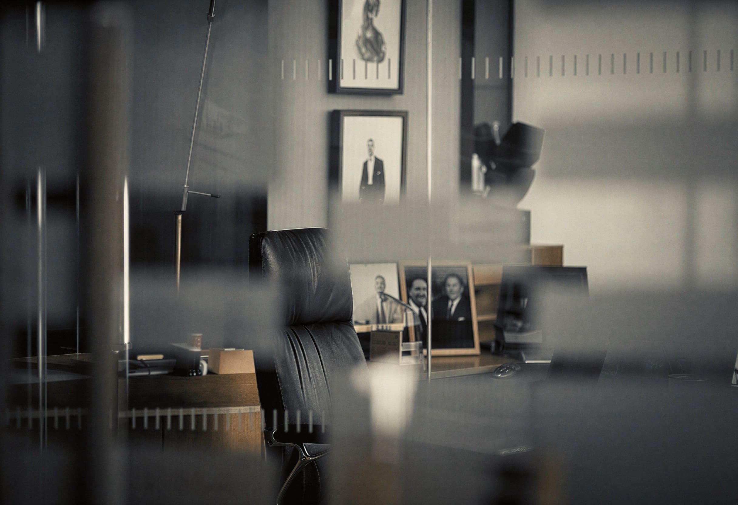 View through a glass partition of a private office, with a black leather chair and desk