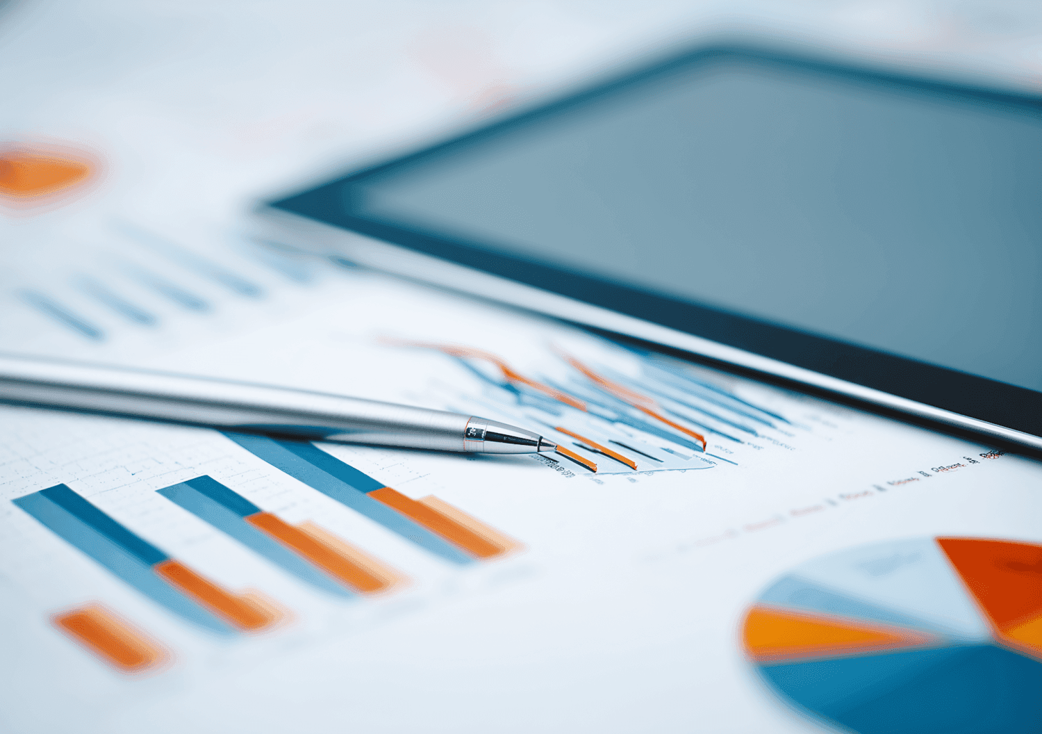Pen and financial charts on paper with tablet.