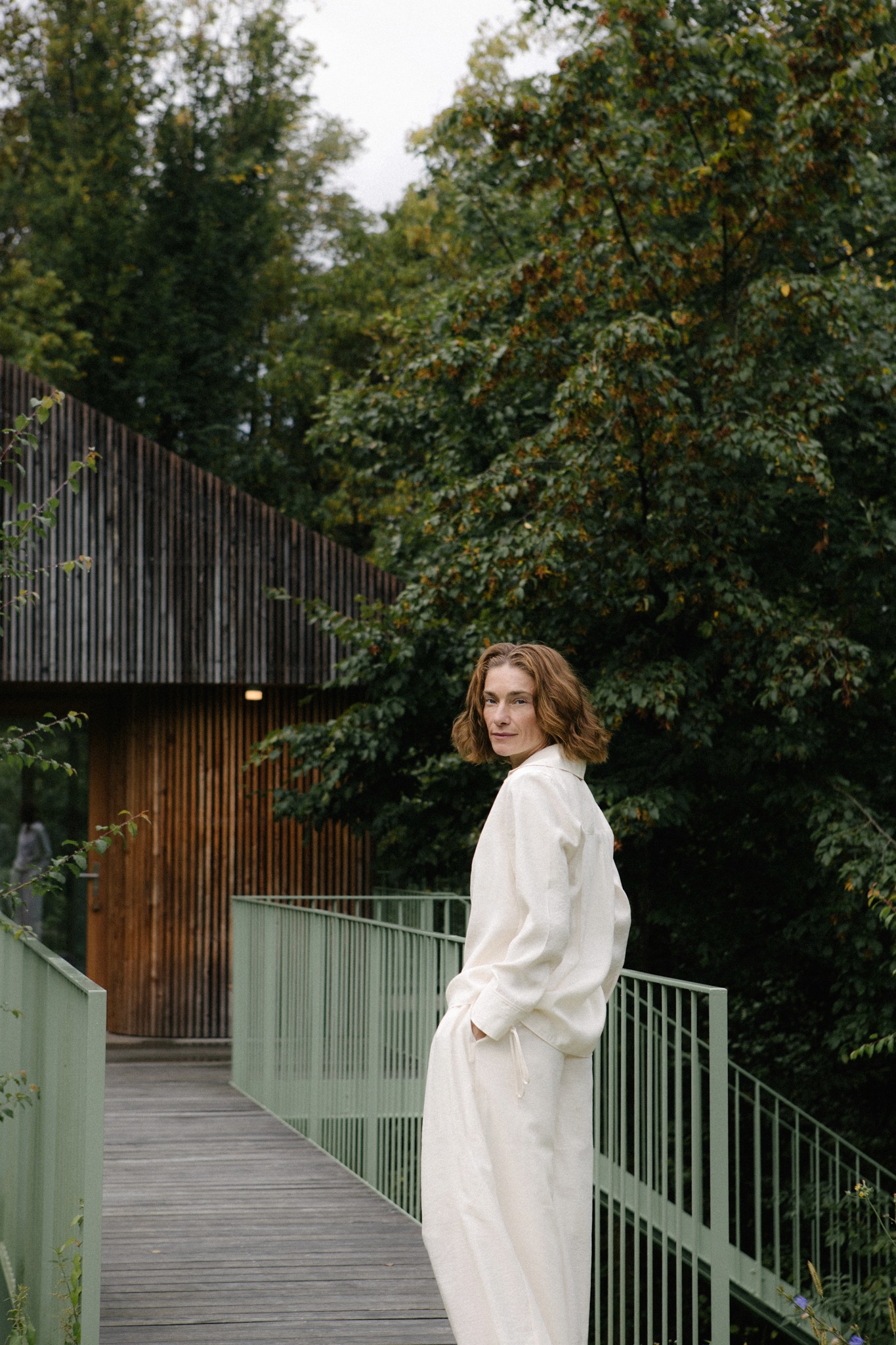 Frau steht auf Steg vor modernem Holzhaus im Grünen