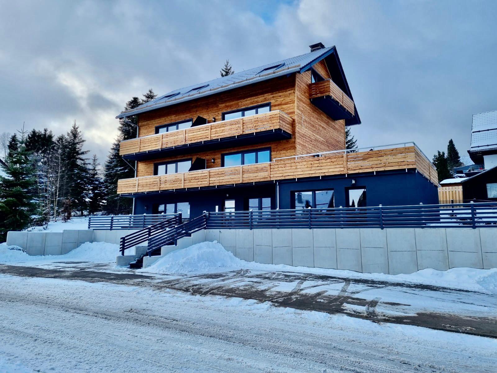 Modern white building with curved glass and reflecting pool.