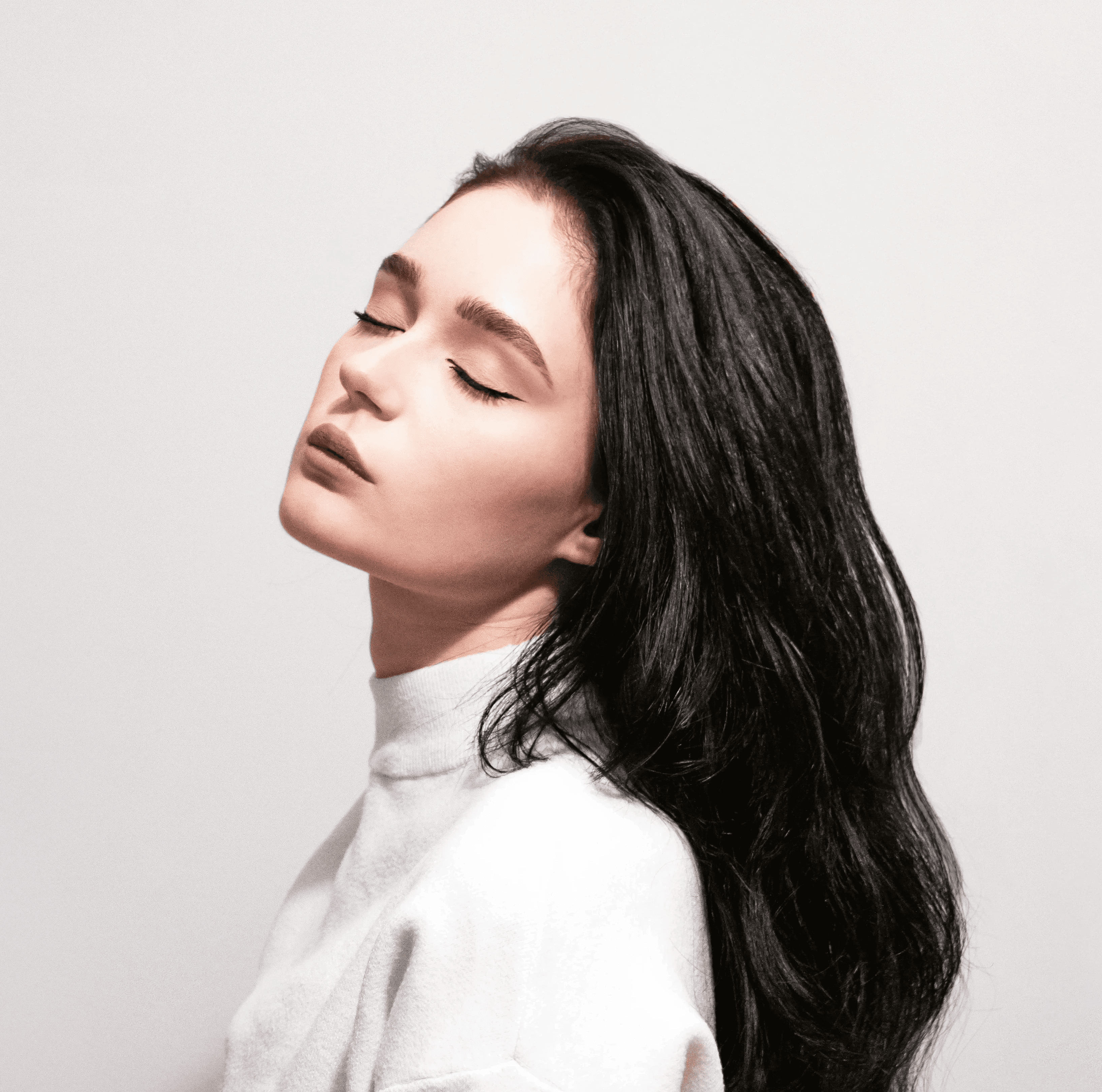a woman with long black hair standing in front of a wall