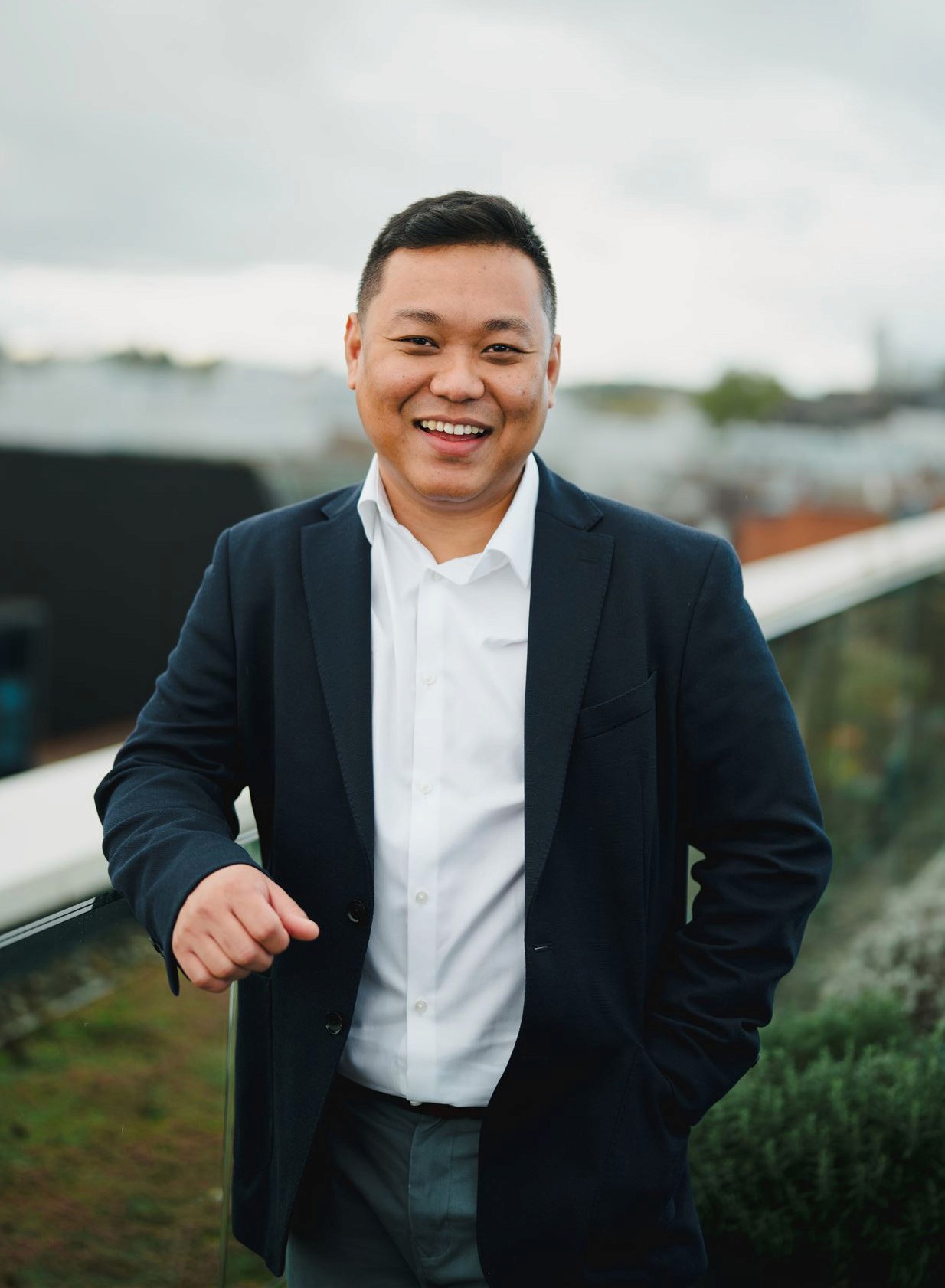 A young man in a white t-shirt stands against a light-colored background.