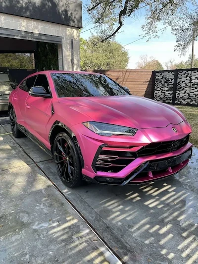 A matte pink Lamborghini Urus parked in a driveway after a professional exterior detail in Houston. The shot highlights the clean, satin finish, deep-cleaned black wheels, and streak-free windows.
