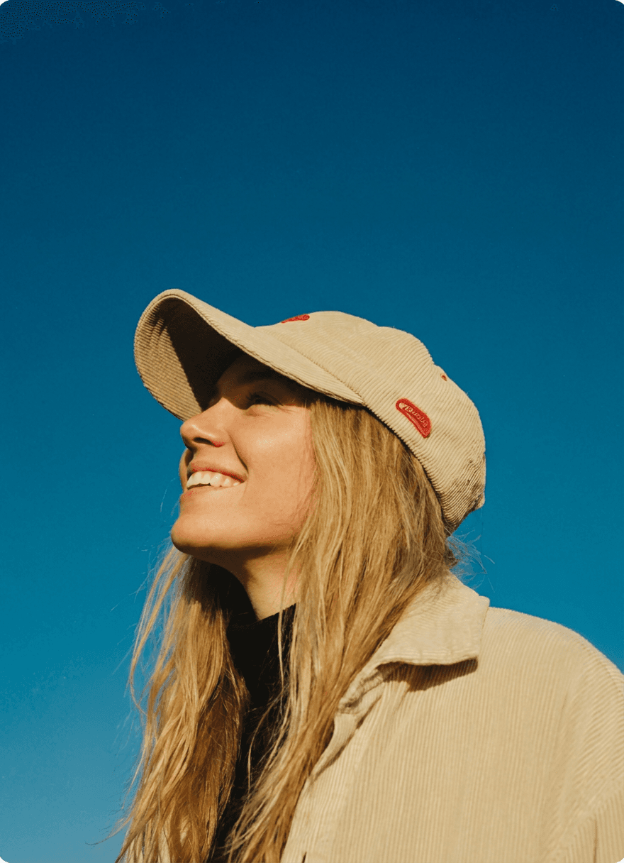 A woman in a baseball cap, blue sky in the background.