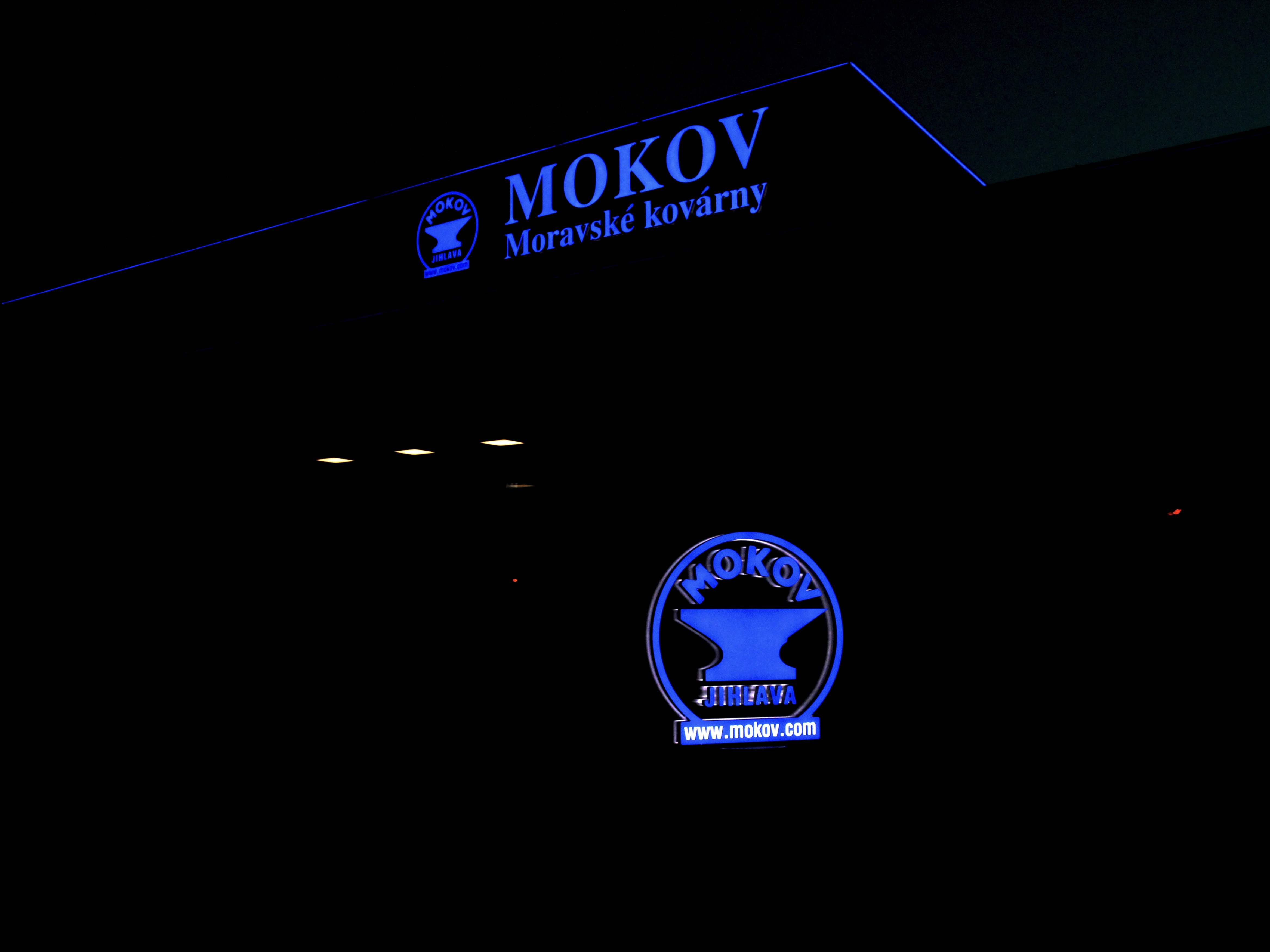 Rozsvícené logo a nápis MOKOV Jihlava na budově kovárny v noci