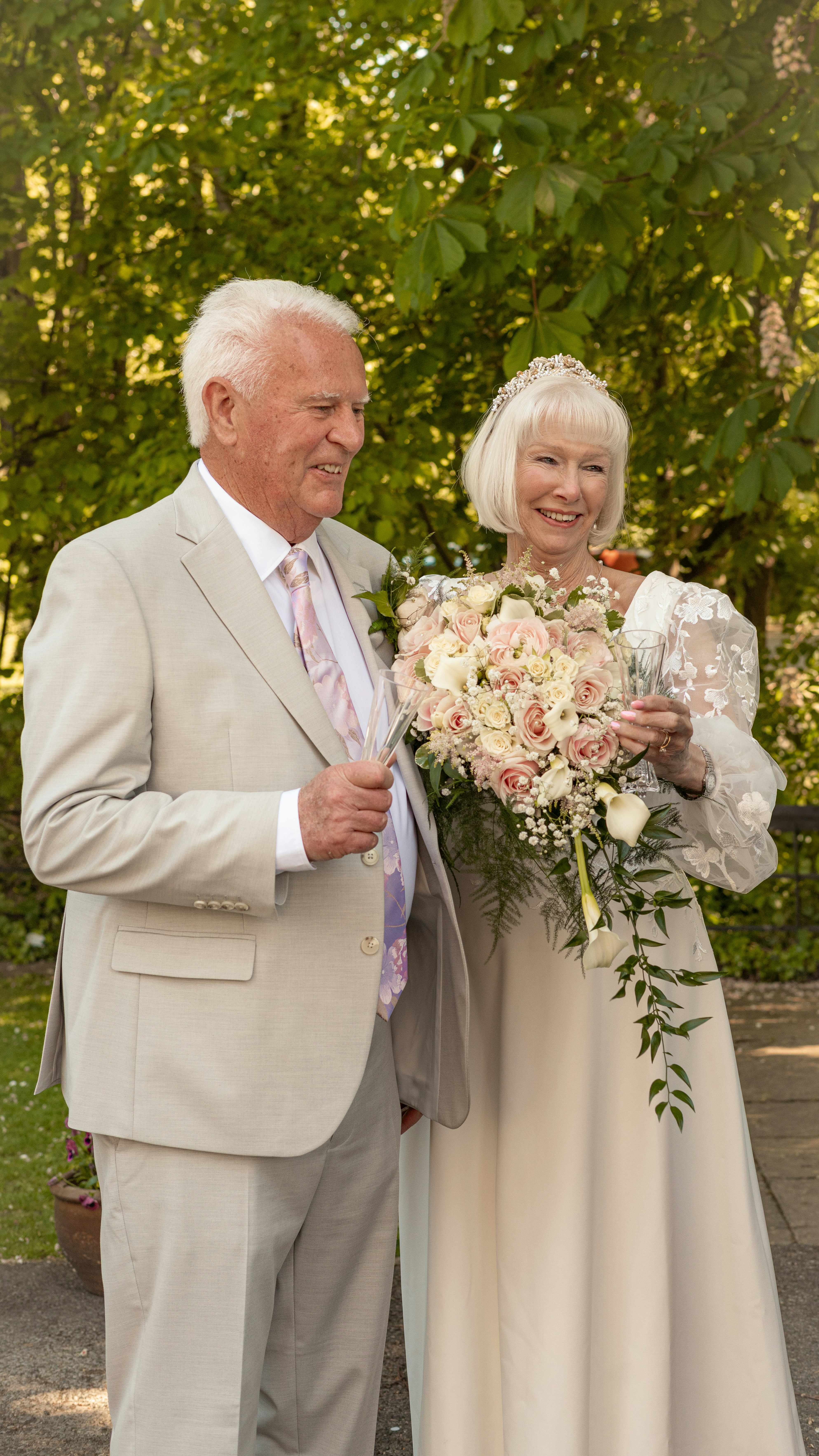 Elderly couple in wedding attire holding flowers