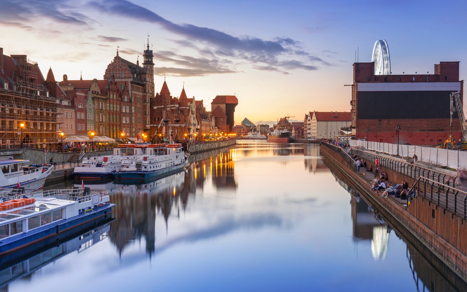 Sunset view of Gdansk River with boats and historic buildings, ideal for a cruise with Prosecco.