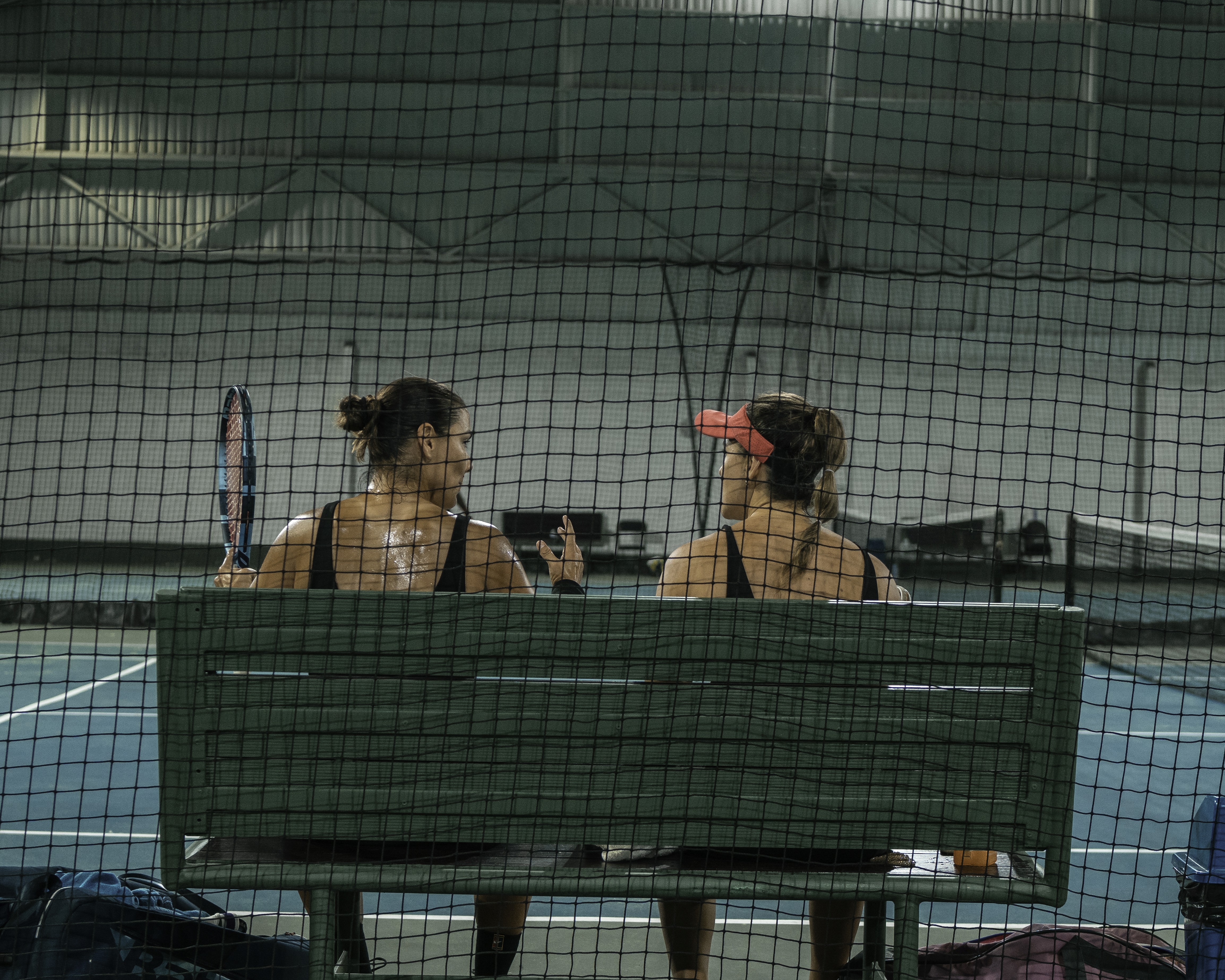 Sun-drenched frontal shot of a modern Mediterranean hotel with arched wooden windows, minimal landscaping, smooth white architecture, calm ocean in the background, cinematic tone.