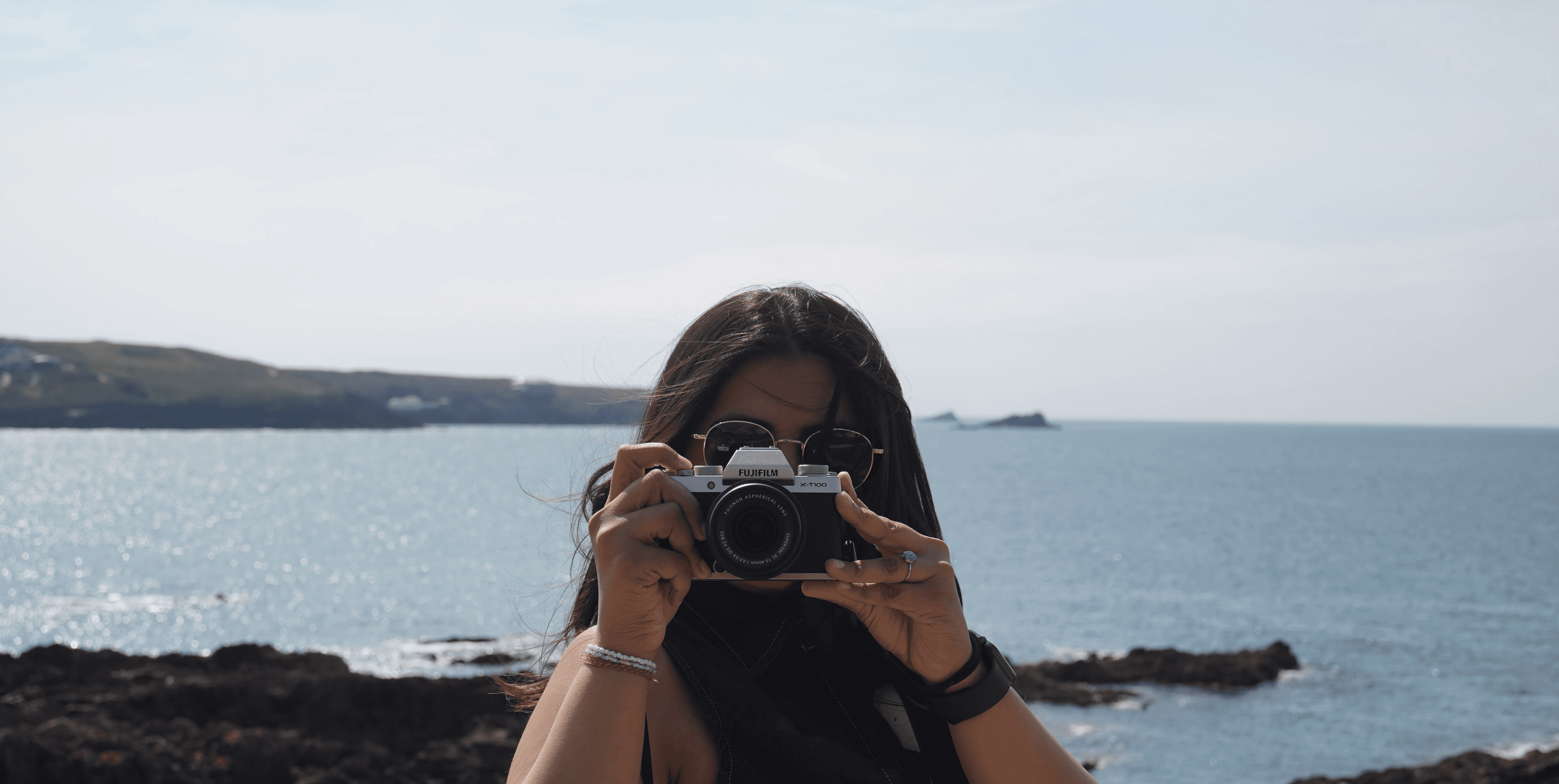 A close-up of a person wearing green-tinted glasses, with a serious expression and smooth skin.