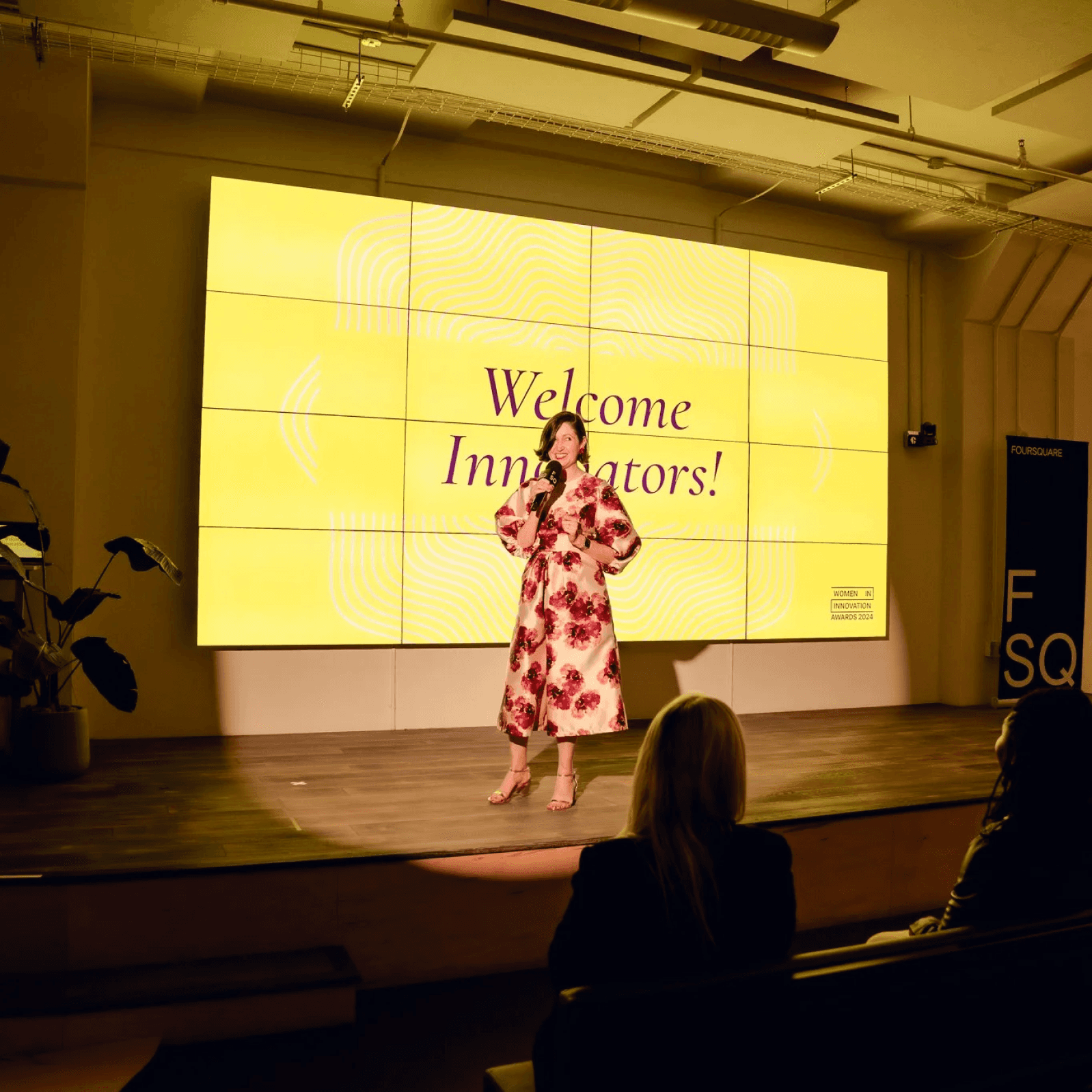 Speaker on stage with the words "Welcome Innovators" on a slide behind her