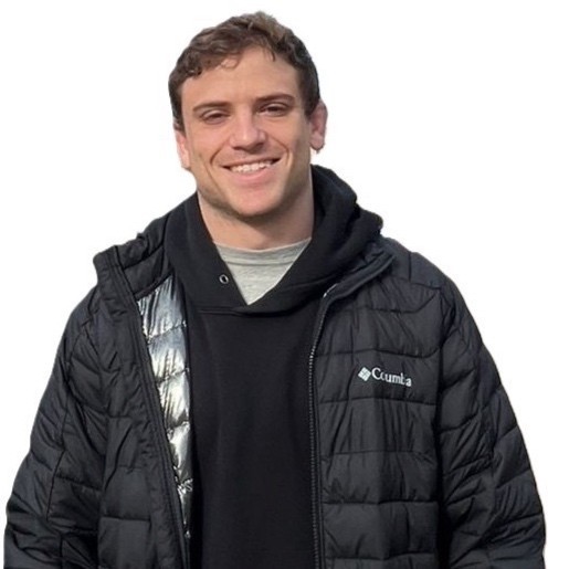 Confident woman with long curly hair wearing sunglasses and a shimmering top, photographed from a low angle against a deep blue sky.