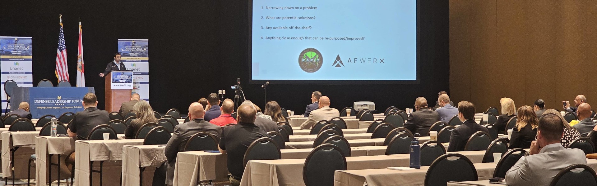 OmniSyn CEO, Rupak Doshi Ph.D., speaking on a stage