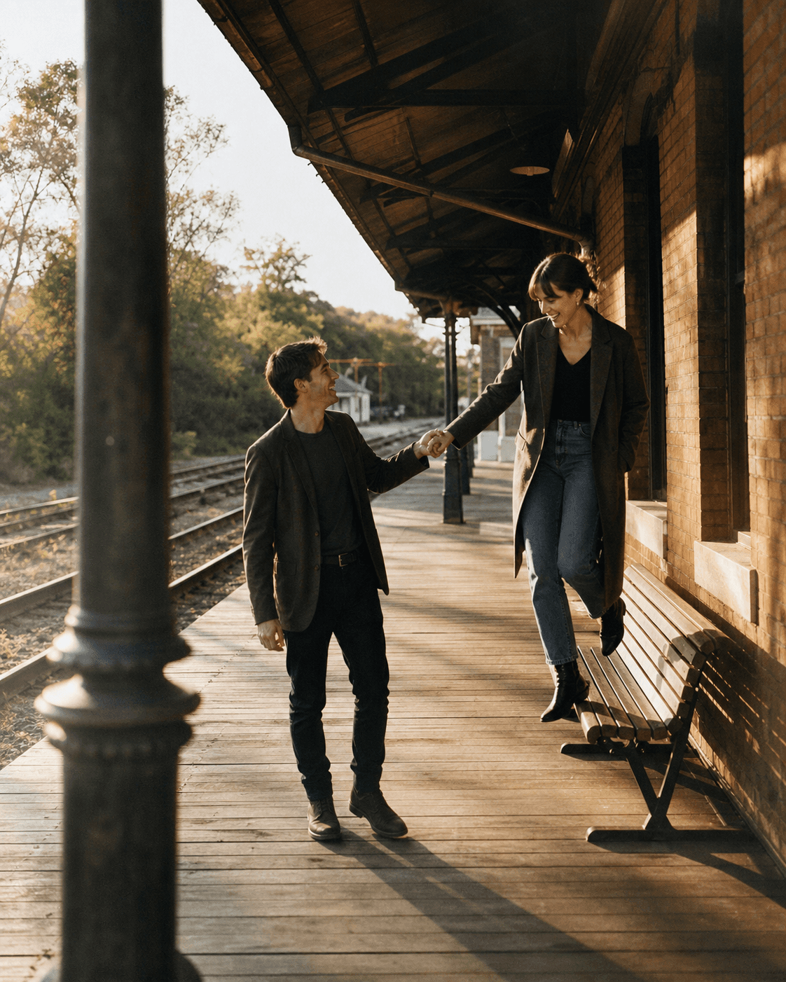 Couple walking along an old train station platform at sunset