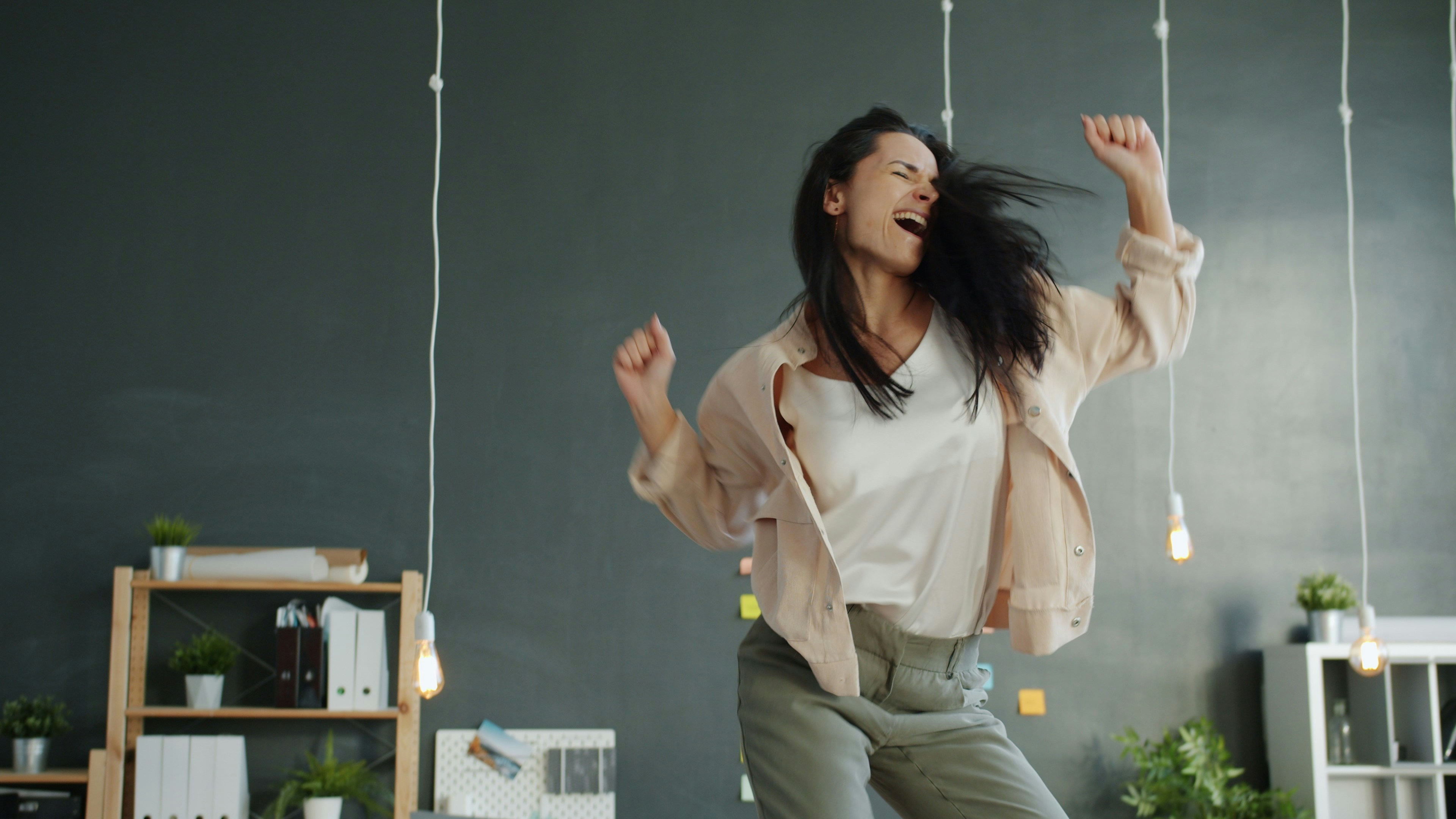 A woman joyfully dancing with arms raised.