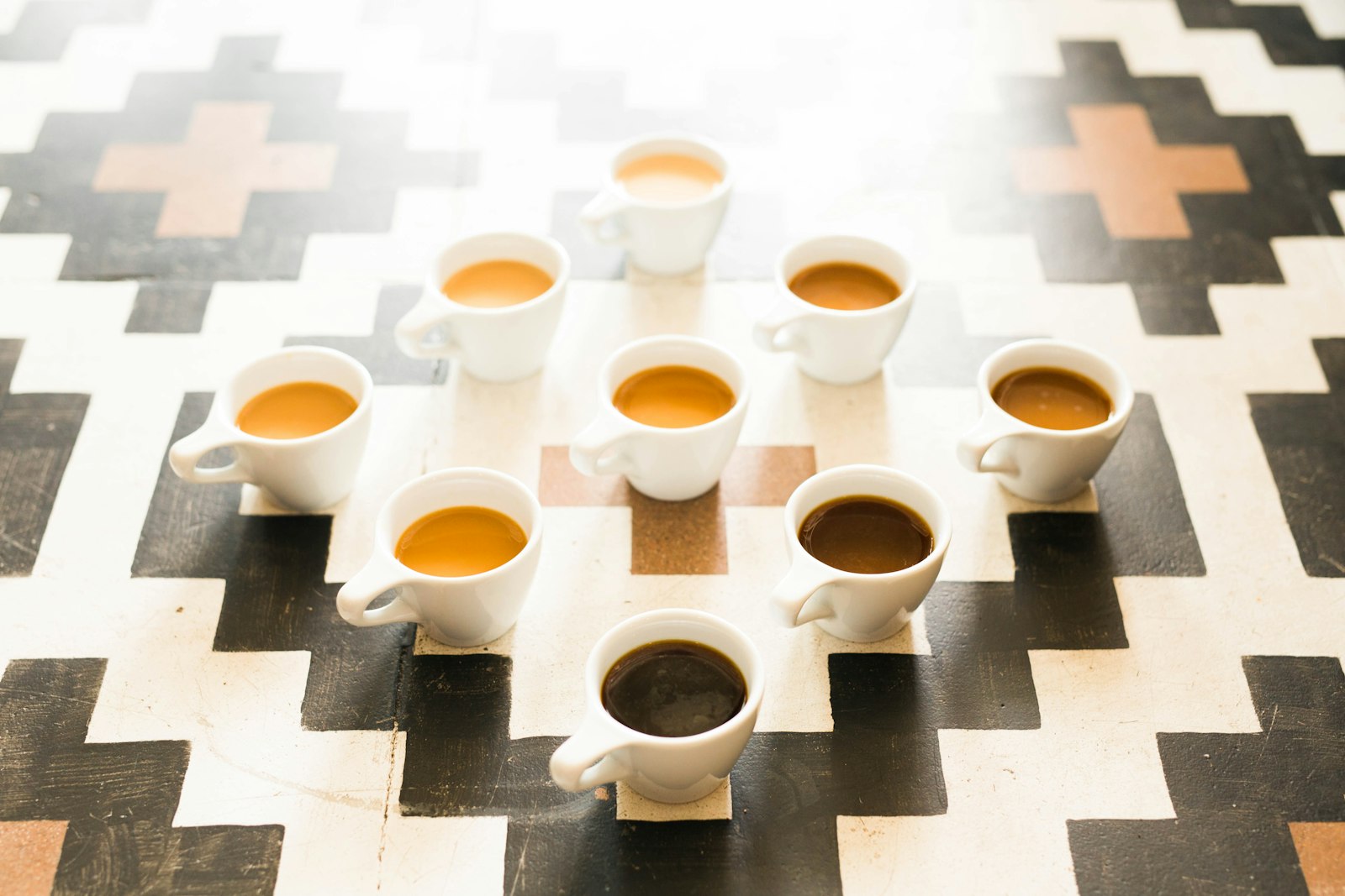 Nueve tazas de café de diferentes preparaciones en fila sobre una mesa