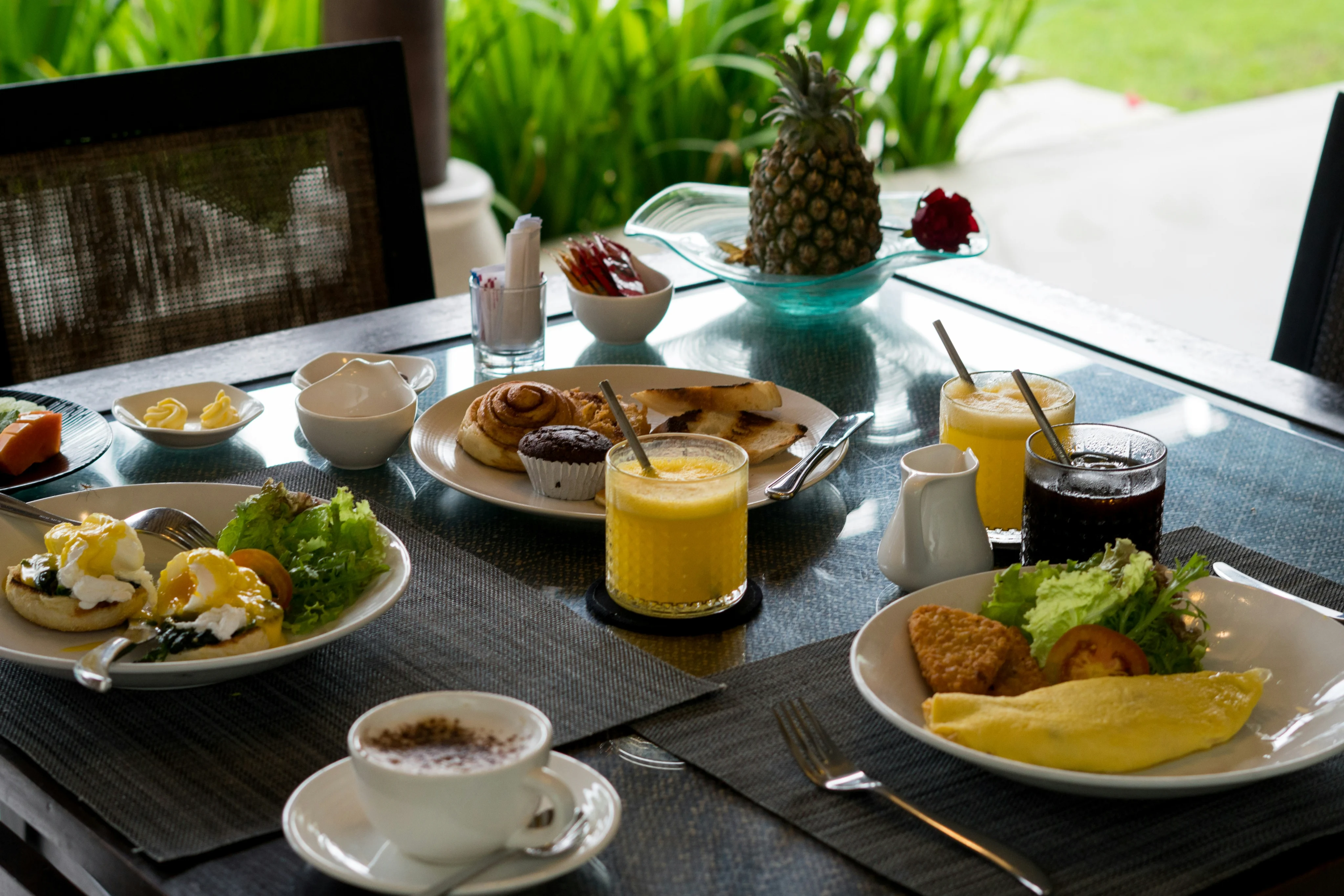 Breakfast table with coffee, fruit, pastries, eggs, and juice.
