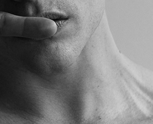 Black and white close-up of a person’s lower face, highlighting lips and jawline in high contrast lighting.