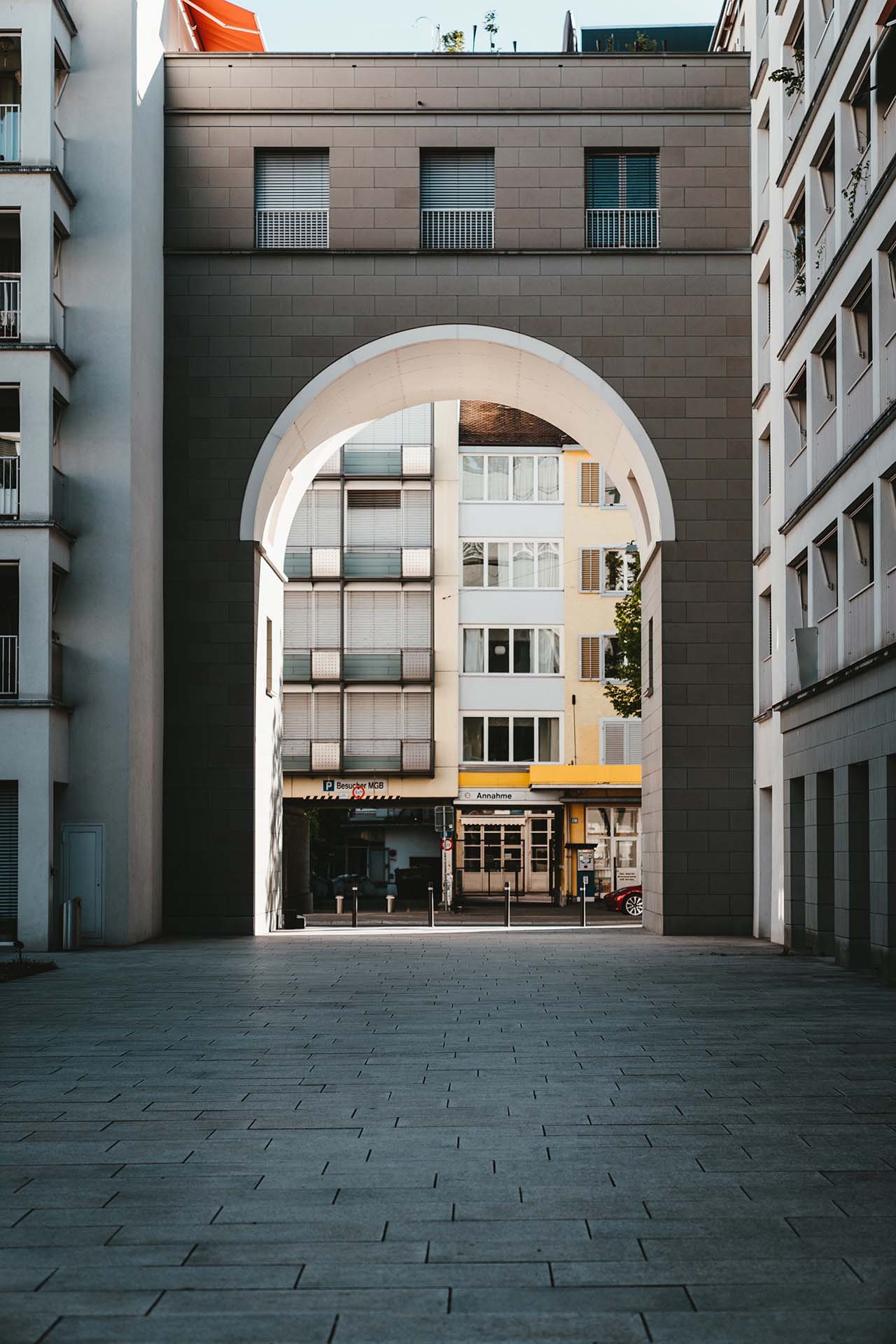A high-contrast architectural photo of a modern Swiss building seen through a large grey archway. This art direction captures the urban living and real estate market context in Switzerland, reflecting the studio's ability to align brand photography with the platform's core industry.