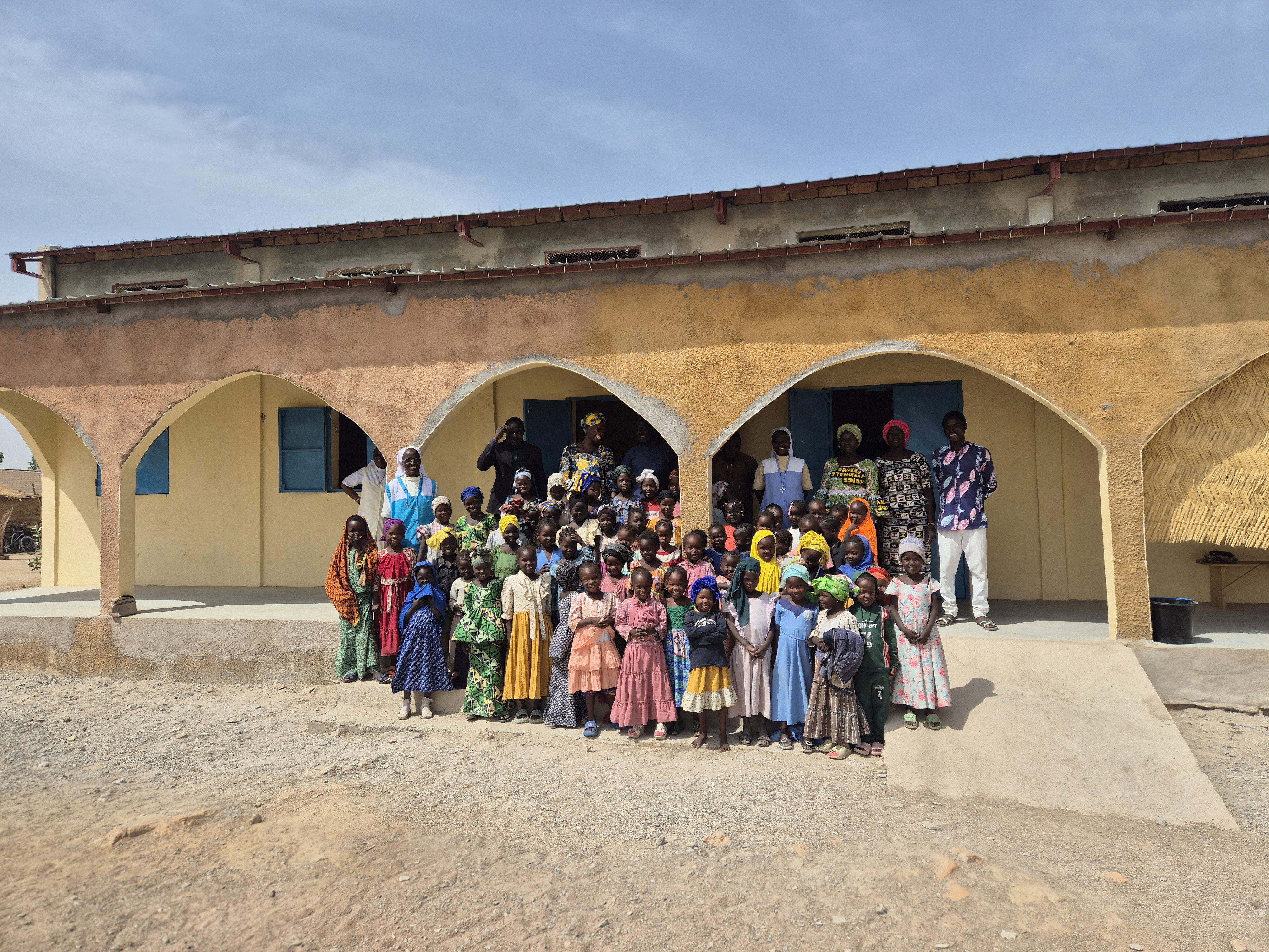 five children smiling while doing peace hand sign