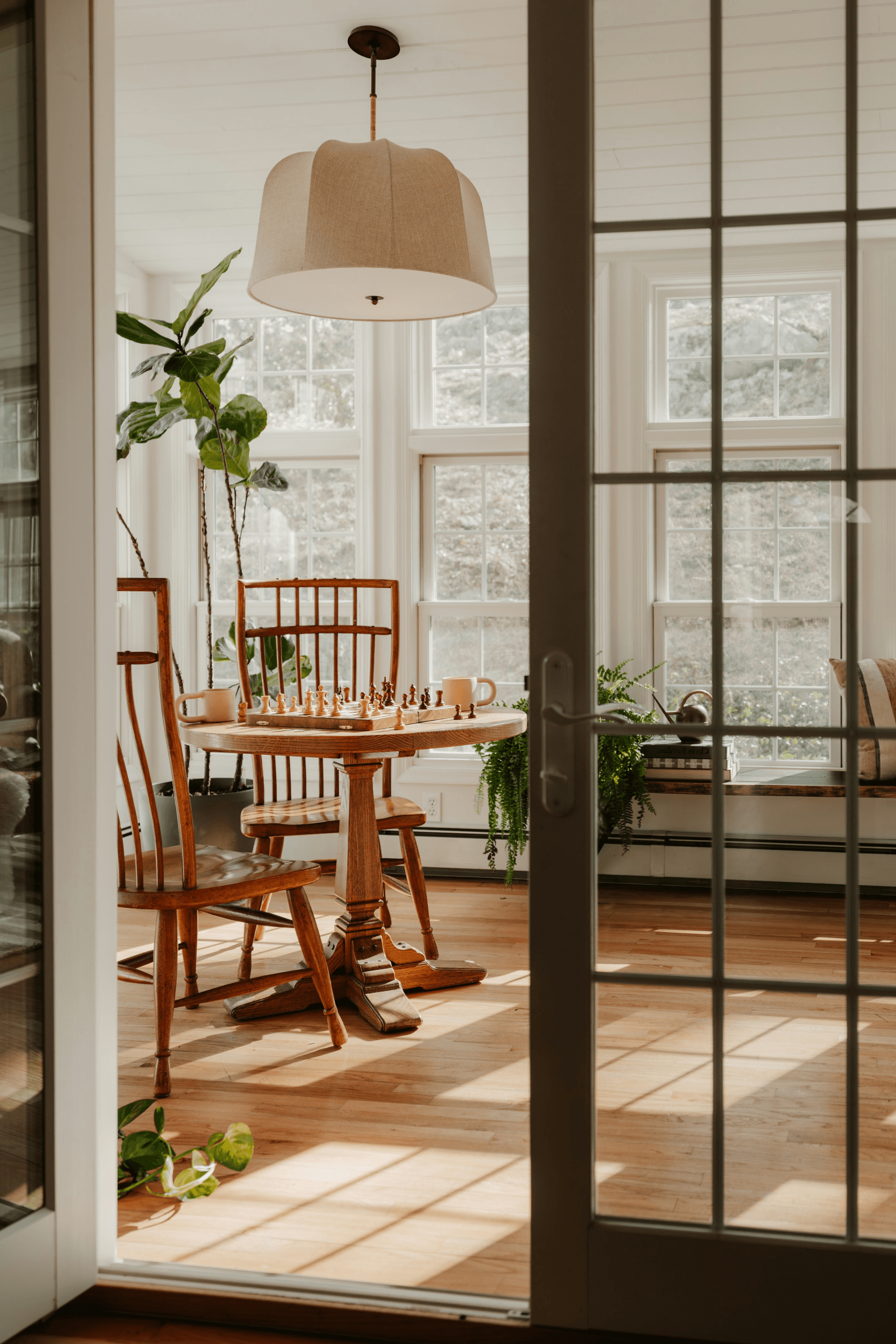 Sunlit cottage nook with vintage wood table, chess set, and French doors