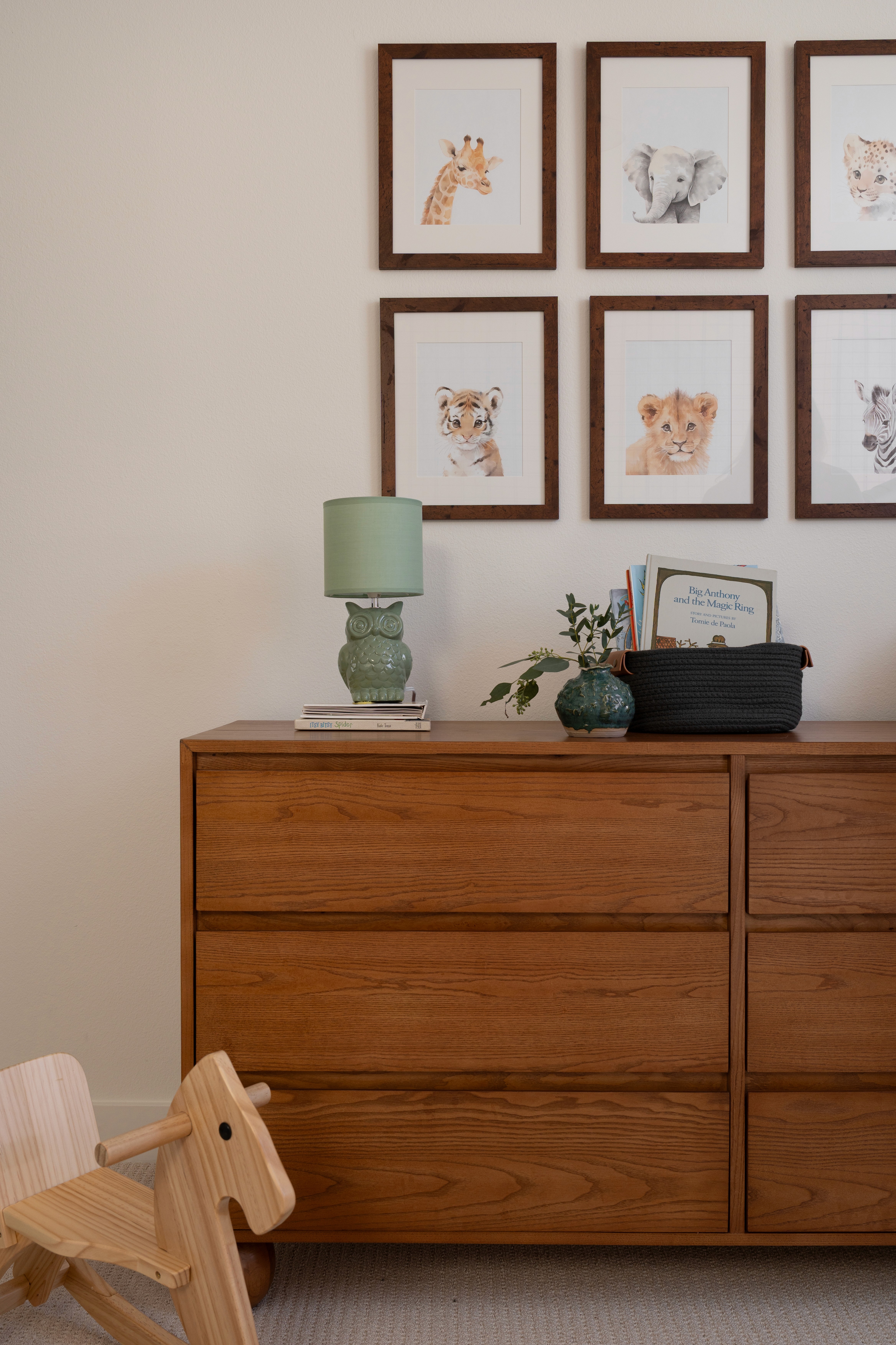 View of animal baby gallery wall, rocking chair, dresser and books