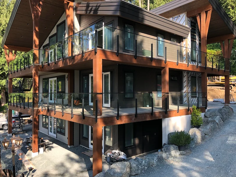 Three-storey home with wood post glass railing system providing clear sightlines across multiple balconies.