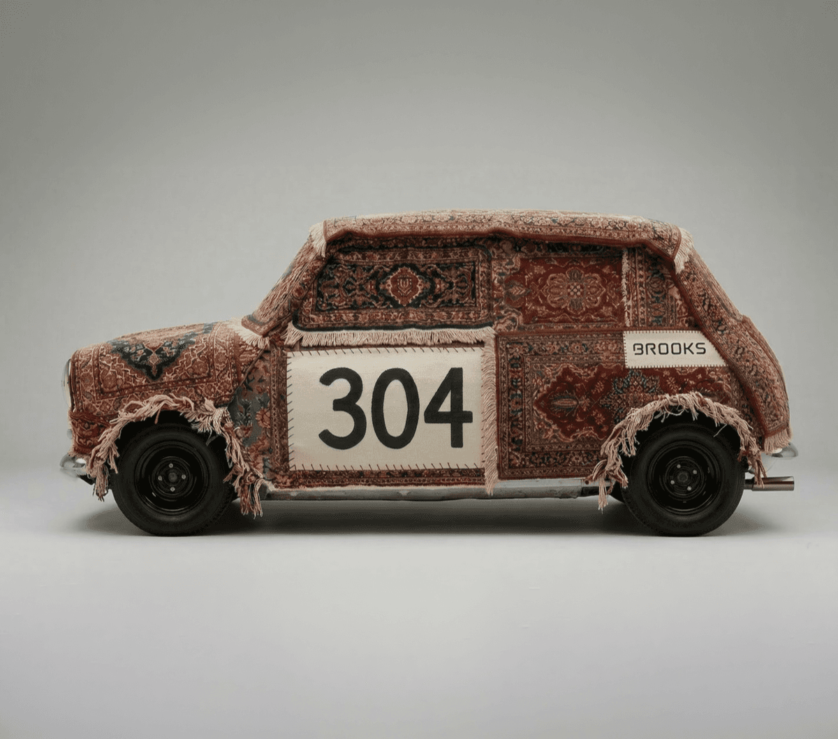 Mini car covered in patterned rugs, with '304' and 'BROOKS'.