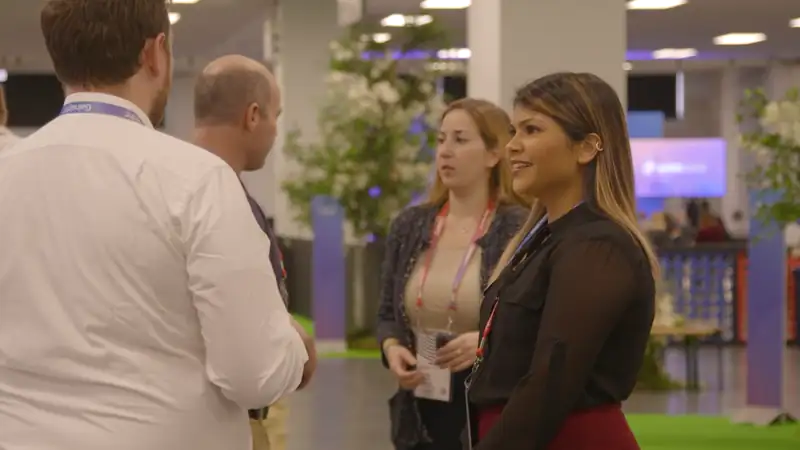 Conference attendees wearing badges talk and network on the Gainsight Pulse exhibition floor.