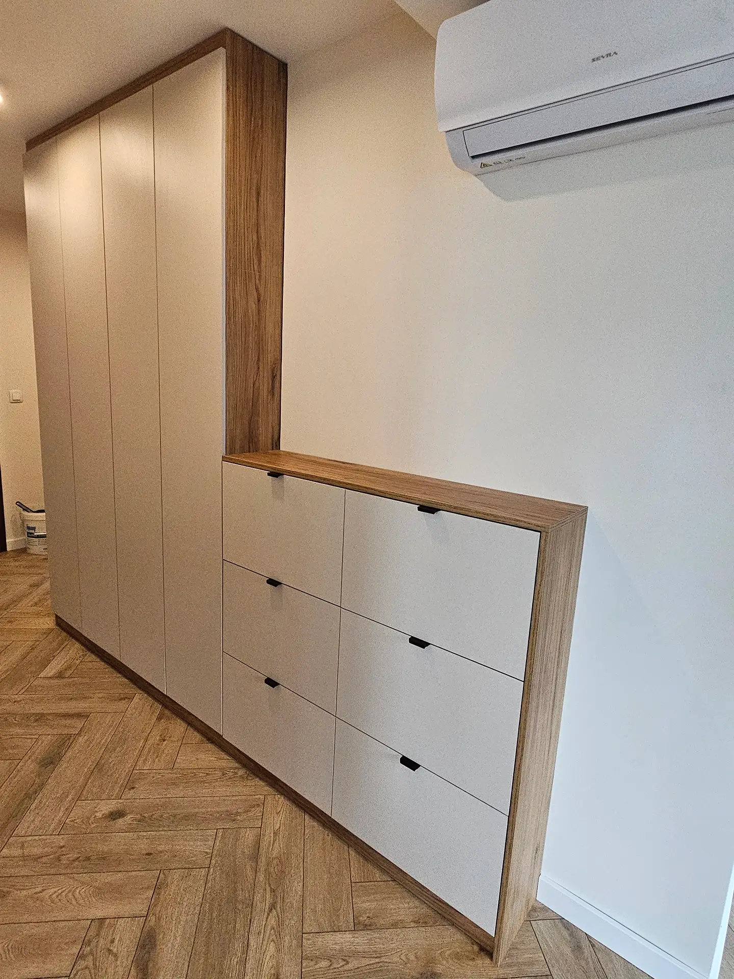 Nowoczesna biała zabudowa meblowa ze schodkową konstrukcją i szafkami na wymiar.