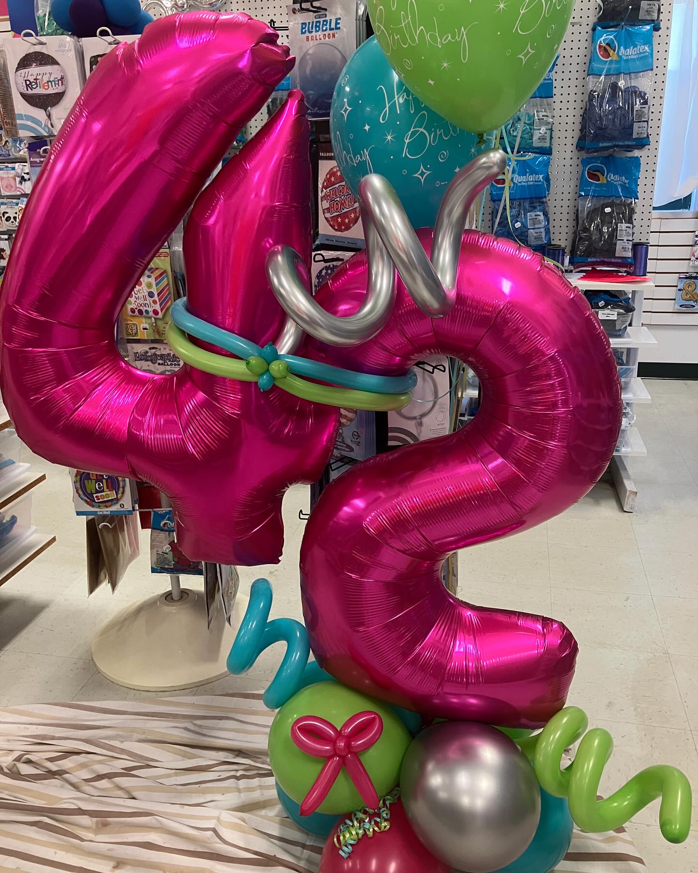Bright pink number 45 balloon centerpiece with green and blue balloon accents created by Be Bold Balloons