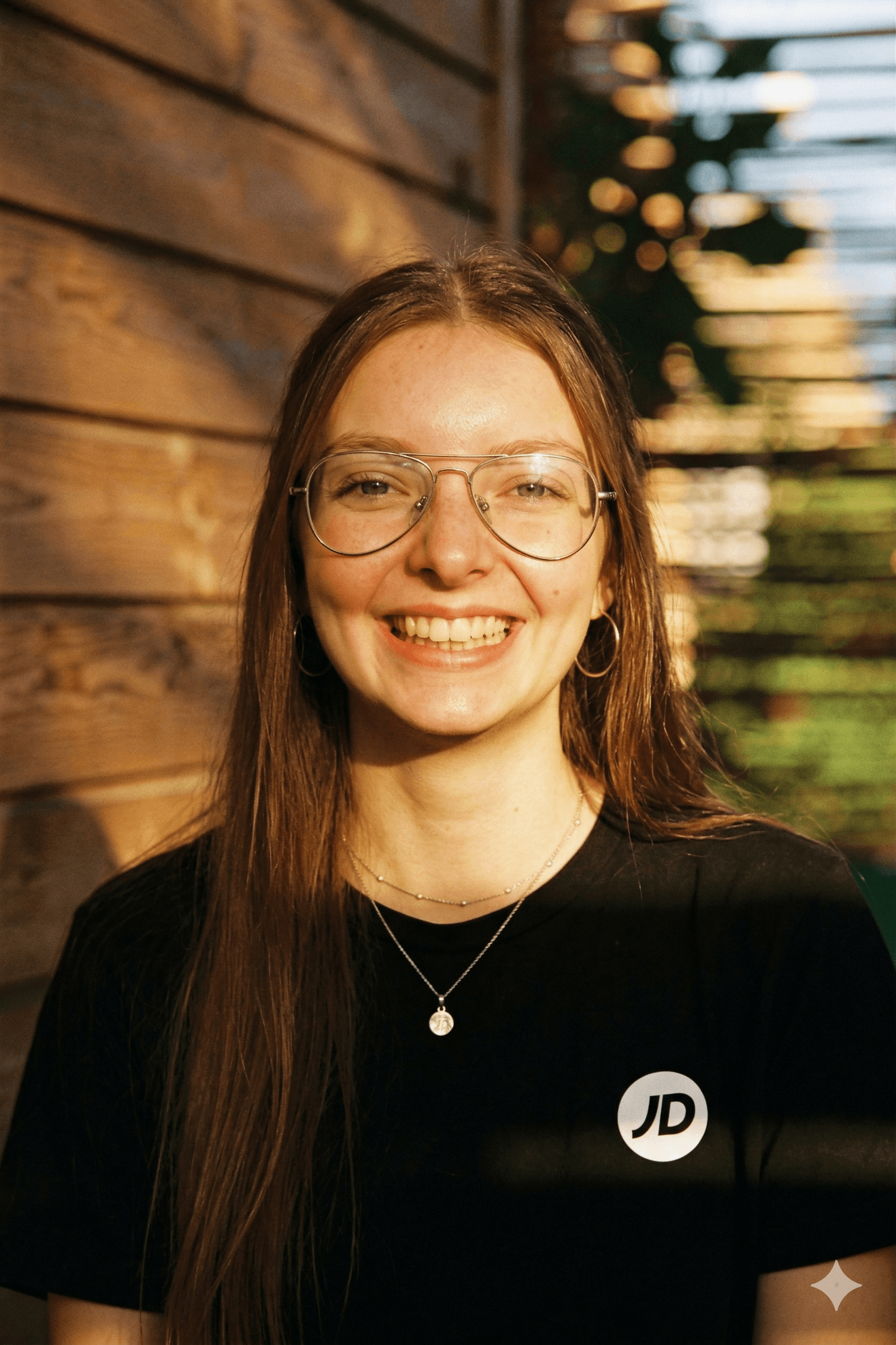 A young woman with blonde hair smiling outdoors.