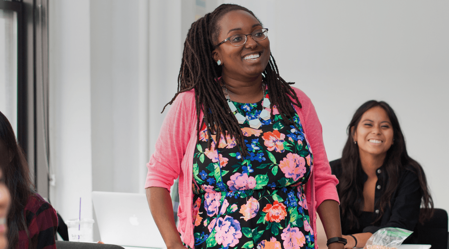 A young designer working at a laptop, focused and self-directed in a dark studio.