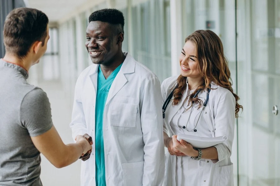 doctors-shaking-hands-with-patient-standing-corridor-hospital