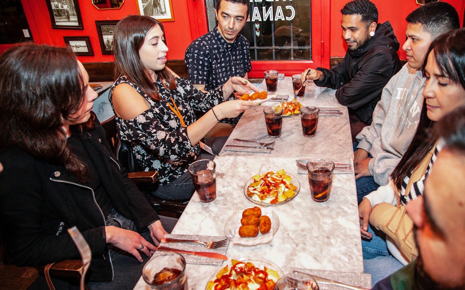 Baráti társaság tapasokat élvez egy asztalnál egy 3 órás, idegenvezetős gasztronómiai túra során La Barceloneta-ban.