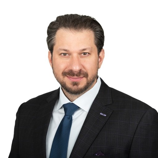 Chris Warren, a professional with a neat beard, smiling confidently in a dark plaid suit and blue tie representing.