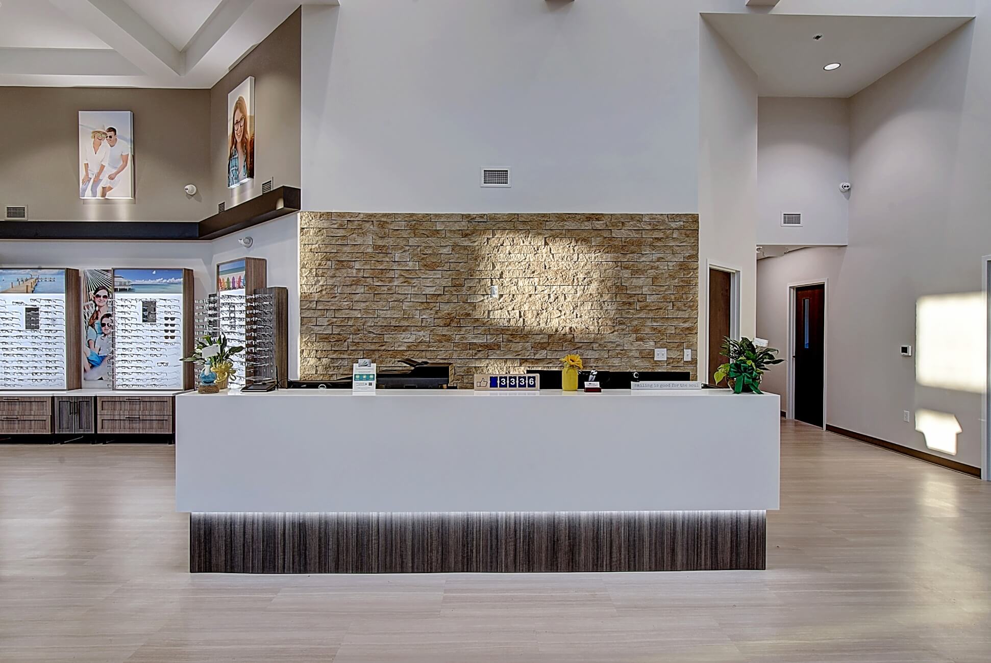 Modern reception area with a sleek counter, artistic wall piece, and minimalist decor, featuring white and wood tones.
