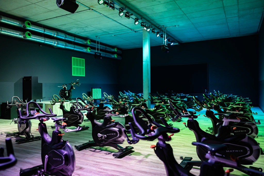 Geräumiger Spinning-Kursraum im XTRAFIT Mainz mit modernen Fahrrädern und stimmungsvoller Beleuchtung.