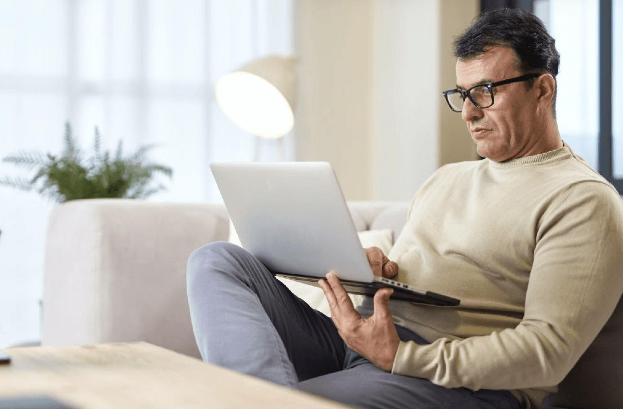 man on couch looking at laptop computer